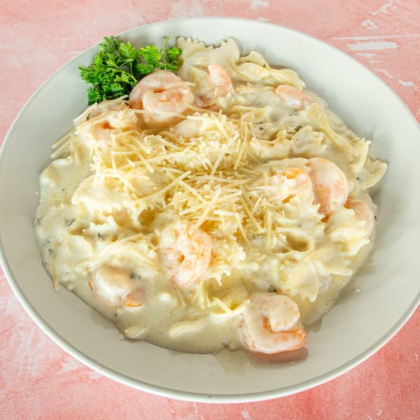 Redbone's creamy shrimp pasta with farfalle, parmesan, and parsley on a white plate.