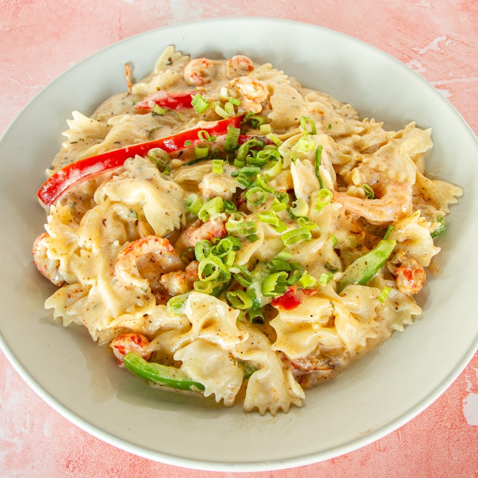 Creamy Cajun pasta with shrimp, crawfish, red and green bell peppers, and green onions.